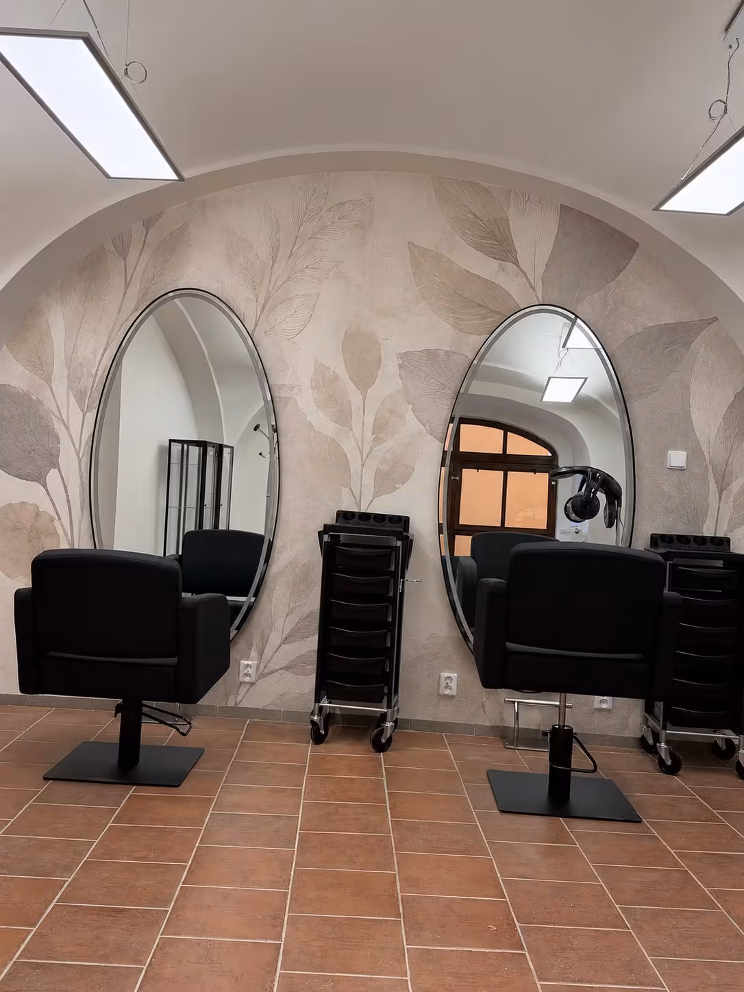 Salón 1602 - kadeřnická křesla a oválná zrcadla pod klenbou